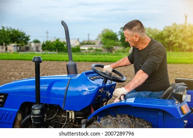 A farmer is driving a tractor. Agro industry, agribusiness. Farming, agriculture. Countryside farmland. Small farms. Work in the agricultural industry. - Shutterstock ID 2007289796