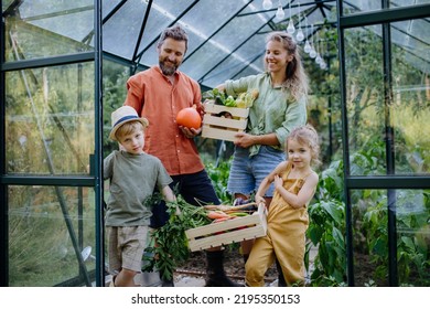 Farmer family with fresh harvest standing in a greenhouse - Powered by Shutterstock