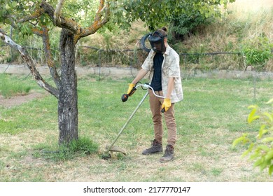 Farmer With Farm Equipment Working In His Garden And Removing Grasses From His Meadow In Summer