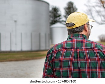 Farmer in flannel shirt standing in front of grain silos