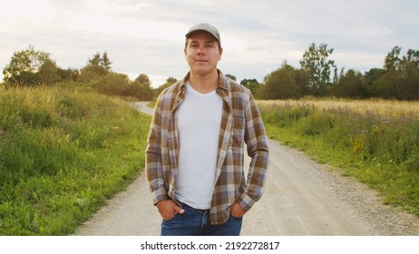 Farmer In Front Of A Sunset Agricultural Landscape. Man In A Countryside Field. Country Life, Food Production, Farming And Country Lifestyle.