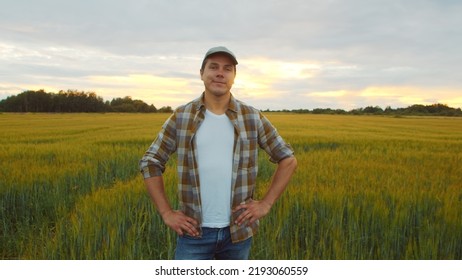 Farmer In Front Of A Sunset Agricultural Landscape. Man In A Countryside Field. Country Life, Food Production, Farming And Country Lifestyle.