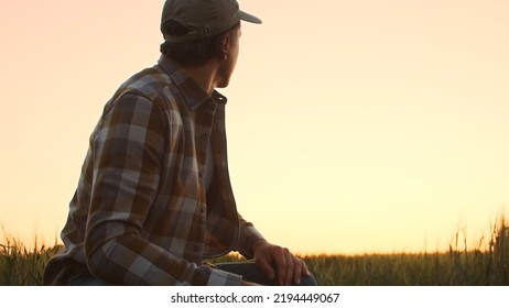 Farmer In Front Of A Sunset Agricultural Landscape. Man In A Countryside Field. Country Life, Food Production, Farming And Country Lifestyle Concept.