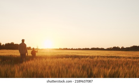 Farmer and his son in front of a sunset agricultural landscape. Man and a boy in a countryside field. Fatherhood, country life, farming and country lifestyle. - Shutterstock ID 2189637087
