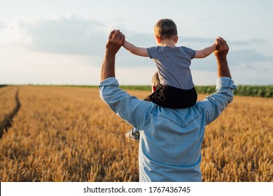 Farmer Holding His Grandson Standing In Wheat Field