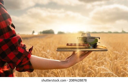 Farmer holding a tablet with a combine harvester. Digital transformation in agriculture. Smart farming concept