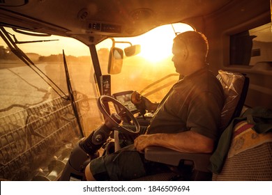 Farmer Inside A Combine During Harvest At Sunset