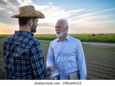 Farmer And Insurance Sales Rep Representative Reaching Agreement Deal. Two Men Agronomist Shaking Hands Standing In Field Happy Satisfied.