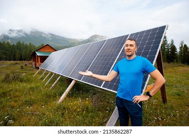 Farmer Man Smiles And Shows Solar Panels In Country House In Mountains, Life In Iceland, Sweden, Finland And Russia.