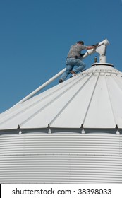 A Farmer On Top Of A Grain Bin