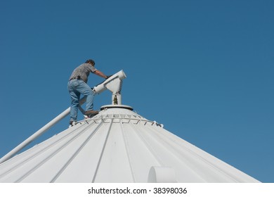 A Farmer On Top Of A Grain Bin