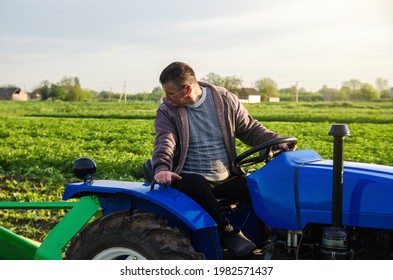 A farmer on a tractor monitors the operation of equipment for harvesting potatoes. Farming and farmland. Simplify speed up work with technology and machines. Agro industry and agribusiness - Shutterstock ID 1982571437
