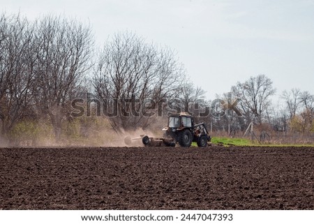 A farmer on a tractor prepares the land with a cultivator for sowing seeds. Agriculture, farming.