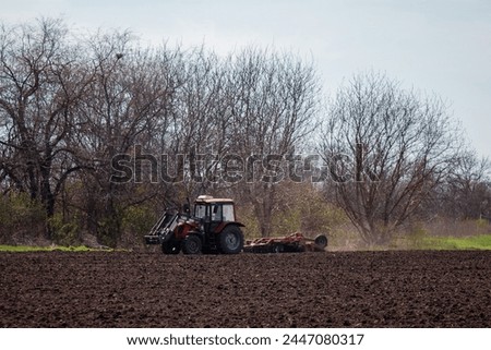 A farmer on a tractor prepares the land with a cultivator for sowing seeds. Agriculture, farming.
