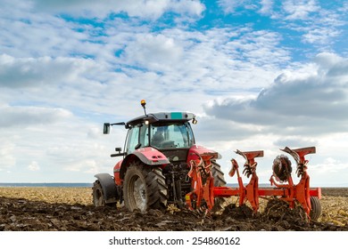 Farmer Plowing Stubble Field With Red Tractor