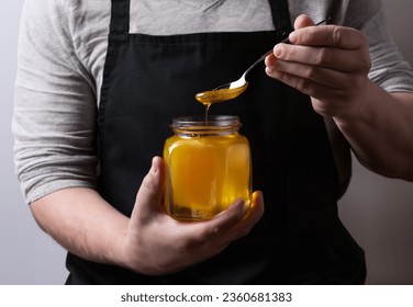 farmer pours a fresh harvest of honey into a glass jar. Organic Honey dripping, pouring from honey dipper in glasses bowl. Close-up - Powered by Shutterstock