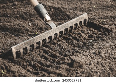 farmer prepares the soil with a rake before planting plants. - Powered by Shutterstock