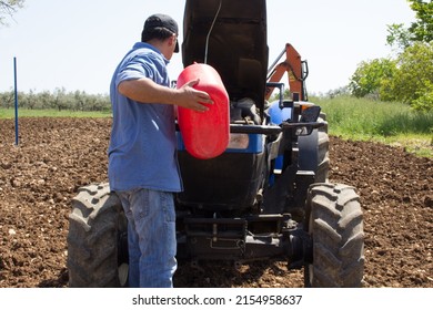 Farmer putting diesel fuel to the tractor with a jerrycan. Reference to expensive fuel in the agricultural sector - Powered by Shutterstock