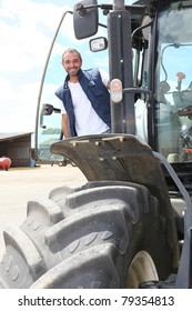 Farmer Standing By The Cab Of His Large Tractor