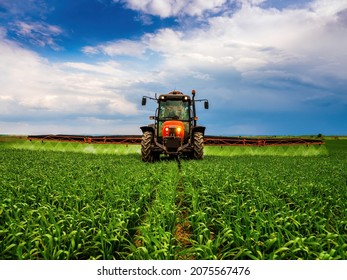 Farmer in tractor at industrial crop farm field spraying green wheat field with herbicides pesticides and fungicides - Shutterstock ID 2075567476