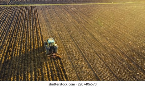 Farmer With Tractor Leveling Land In The Countryside.