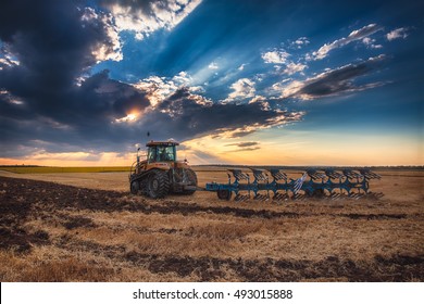 Farmer in tractor preparing land with cultivator and dramatic cloudscape - Shutterstock ID 493015888