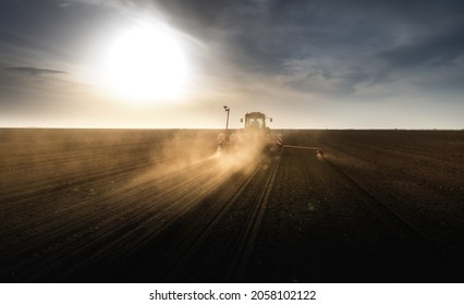 Farmer with tractor seeding - sowing crops at agricultural field. Plants, wheat. - Shutterstock ID 2058102122