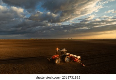 Farmer with tractor seeding - sowing crops at agricultural fields in sunset - Shutterstock ID 2368731885