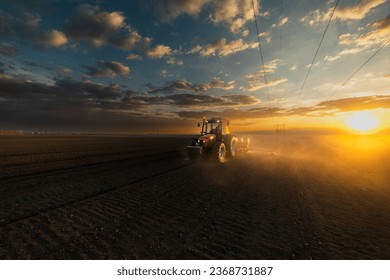 Farmer with tractor seeding - sowing crops at agricultural fields in sunset - Shutterstock ID 2368731887