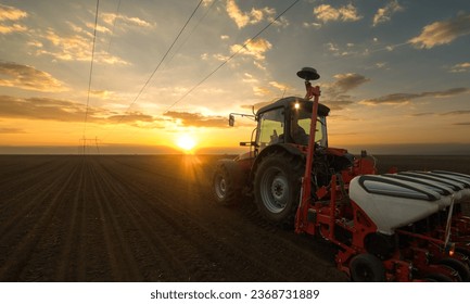 Farmer with tractor seeding - sowing crops at agricultural fields in sunset - Shutterstock ID 2368731889