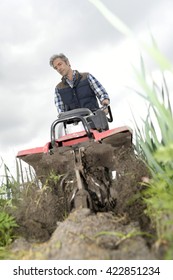 Farmer Using Rototiller In Field