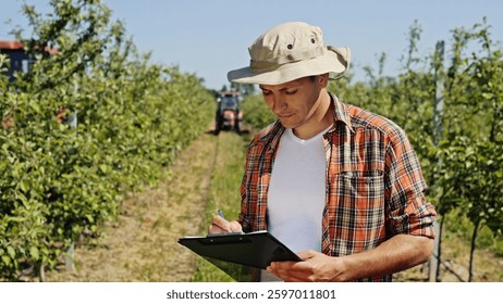 A farmer is using a tablet device in his orchard to effectively manage crop production and care