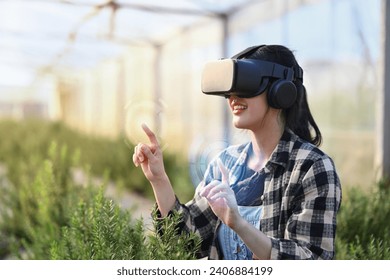 Farmer wearing VR headset for controlling process in greenhouse cultivation. Modern and smart agriculture concept.