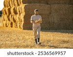 Farmer In Wheat Field After Harvest Examining Hay. Crops After Harvesting. Farm Lifestyle. Barn, Hay Rolled Bales. Hay On Farm. Livestock Farming. Agriculture business farm concept.