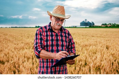 Farmer in a wheat field checking crop and making a notes. Agricultural concept - Powered by Shutterstock