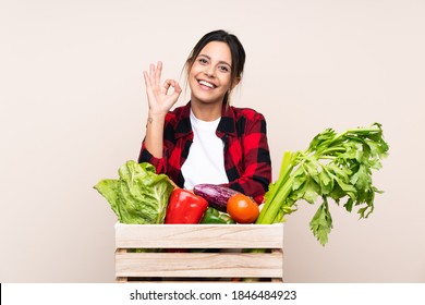 Farmer Woman holding fresh vegetables in a wooden basket showing an ok sign with fingers
