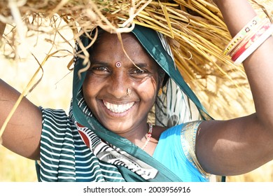 A Farmer woman is smiling while holding crop on head - Shutterstock ID 2003956916