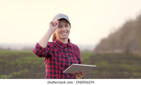 Farmer woman works with a computer tablet, smiles for camera. A smart agronomist with tablet in his hands checks field. Environmentally friendly agriculture. Modern digital technologies in agriculture - Powered by Shutterstock