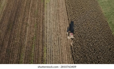 A farmer working in a large field using a tractor in a peaceful rural setting