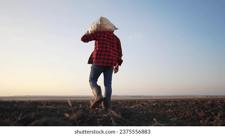 farmer working with sack in agricultural field. agriculture business farm concept. farmer worker carries a bag with harvest at sunset silhouette in agricultural field lifestyle - Powered by Shutterstock