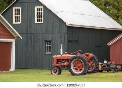 Farming Background. Red antique tractor and traditional barn in the American Midwest.