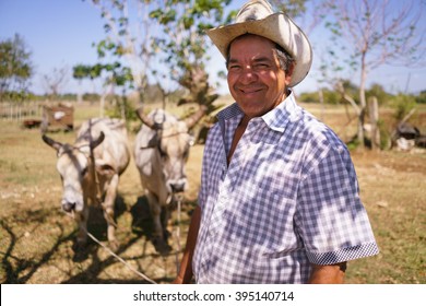 Farming And Cultivations In Latin America. Portrait Of Middle Aged Hispanic Farmer Sitting Proud In His Tractor At Sunset, Holding The Volante. He Looks At The Camera And Smiles Happy.