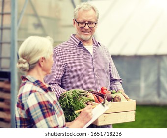 farming, gardening, agriculture, harvesting and people concept - senior couple with box of vegetables and clipboard at farm greenhouse - Powered by Shutterstock