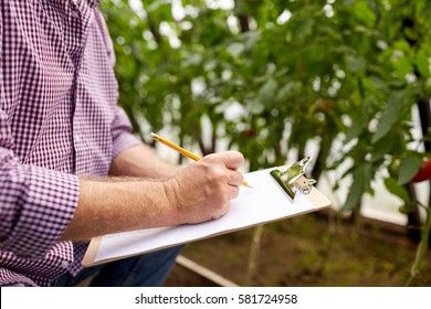 farming, gardening, agriculture and people concept - senior man writing to clipboard at farm greenhouse - Powered by Shutterstock