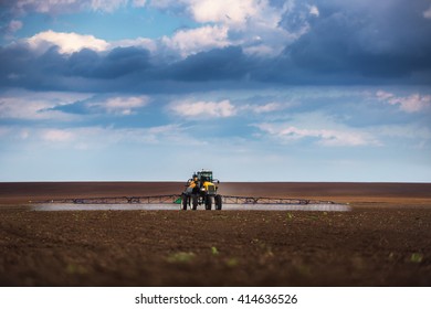 Farming tractor plowing and spraying on field
