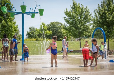 FARMINGTON HILLS, MI / USA - JULY 15, 2019: Children Of Various Ages, Sizes And Colors Enjoy Cooling Off At Heritage Park’s Splash Pad On A Hot Summer Day With Fountains, Sprinklers And Water Toys.