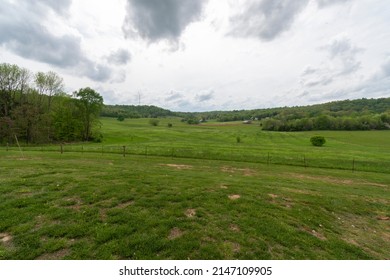 Farmland In Missouri USA, Springtime Green Field Grass And Trees Dark Clouds Moving Under Blue Gray Sky, Country Living At It Best. Picture Of Home Sweet Home America. Horizontal Photo Or Photograph,