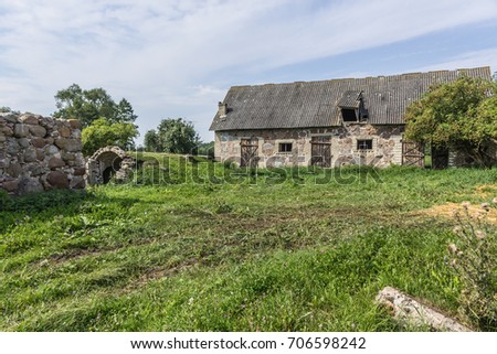 The farmyard is an agricultural abandoned farm. The old collapsed barns. The entrance to the cellar is like a cave. The end of the summer . Podlasie, Poland.