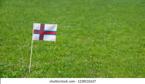 Faroe Islands flag. Photo of Faroe Islands flag on a green grass lawn background. Close up of national flag waving outdoors. - Powered by Shutterstock