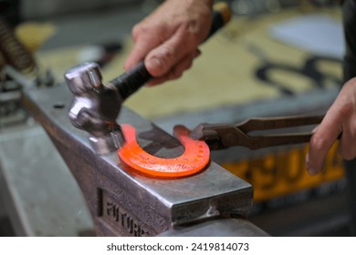 A farrier works on shaping a horseshoe for a horse. - Powered by Shutterstock